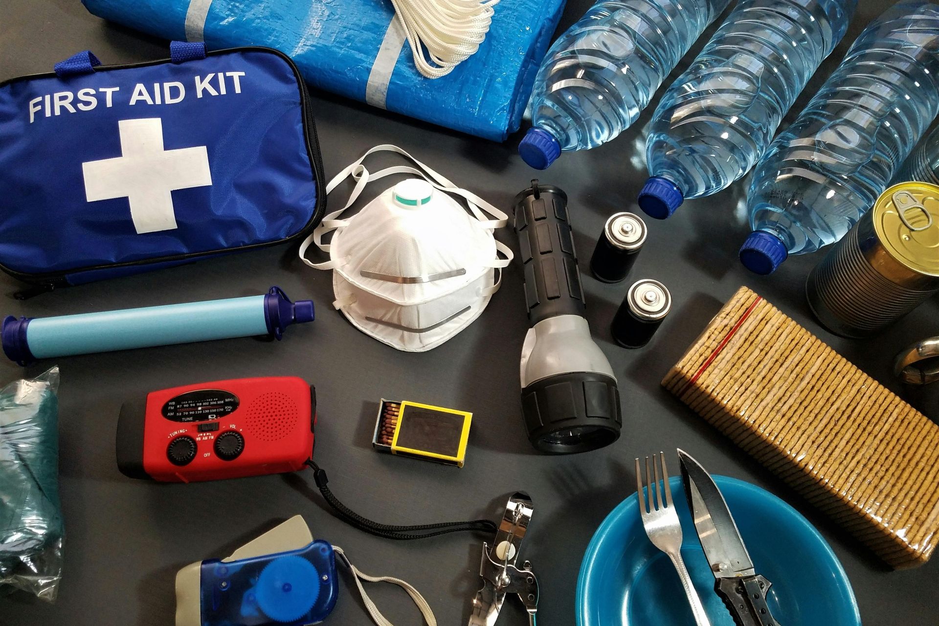 Flat lay of essential emergency survival kit items including first aid and water bottles.