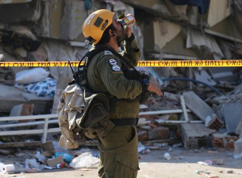 Rescue worker amidst urban rubble post-earthquake, assessing damages.