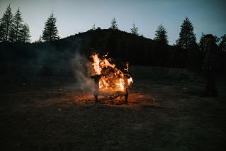 A dramatic outdoor scene with a wooden chair engulfed in flames during dusk.