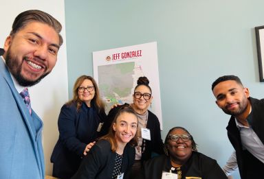 Professionals in a modern office meeting with a green wall backdrop, discussing plans.