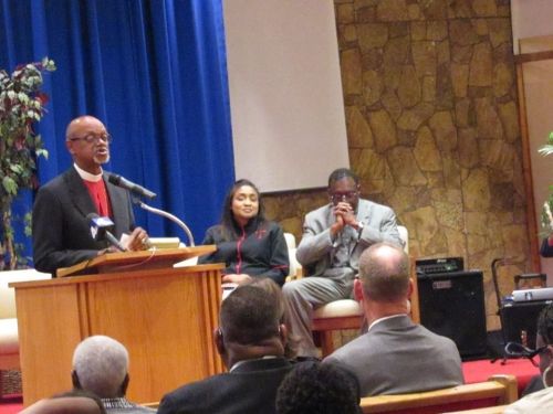 A joyful family comprising parents and a baby relaxing together on the grass in a park.