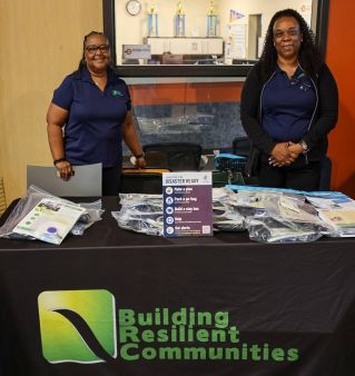 A diverse group of professionals collaborating during an office meeting, using laptops and notebooks.